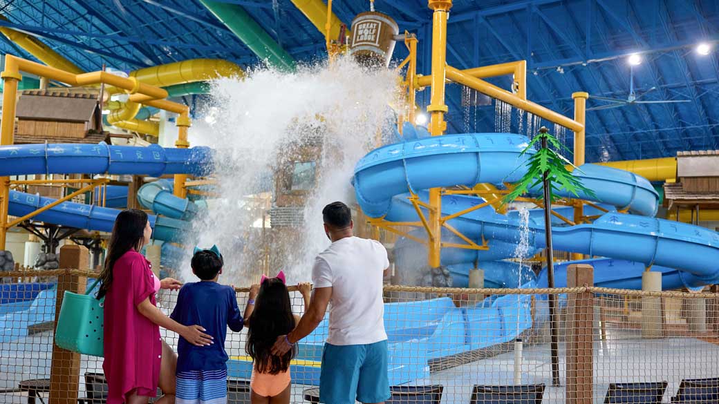 family watching water fall from a large bucket inside a water park