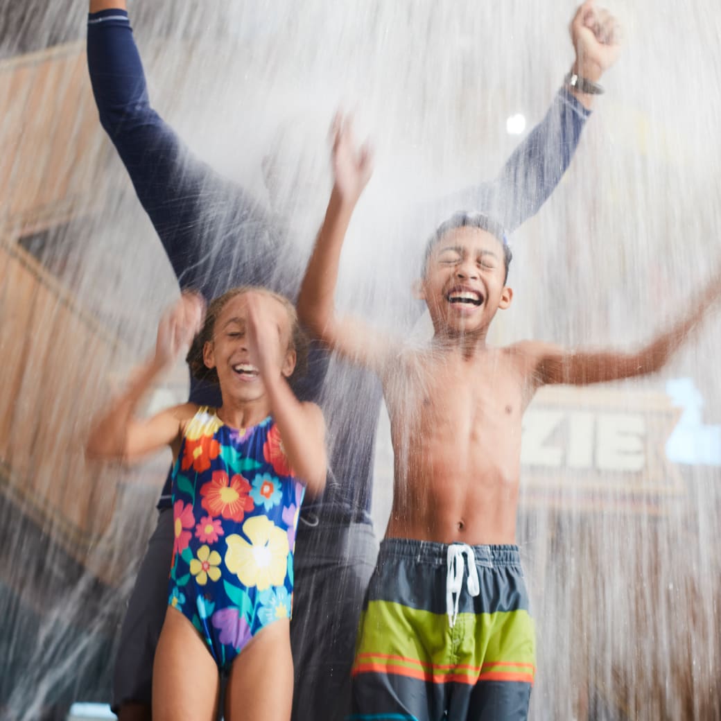 kids enjoy with father as they get soaked in water dropped from the top