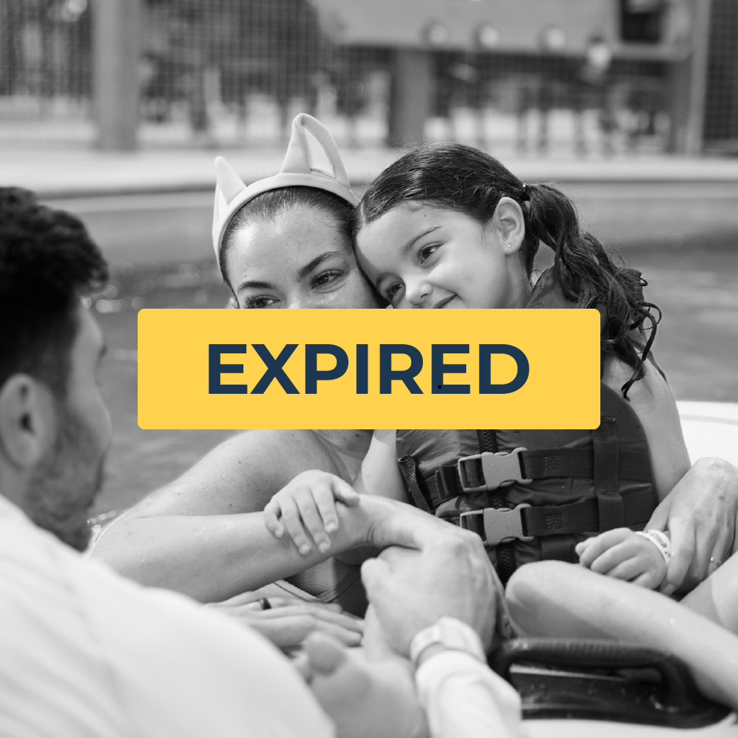 mother and daughter smiling and looking at there father while riding a tube in the pool