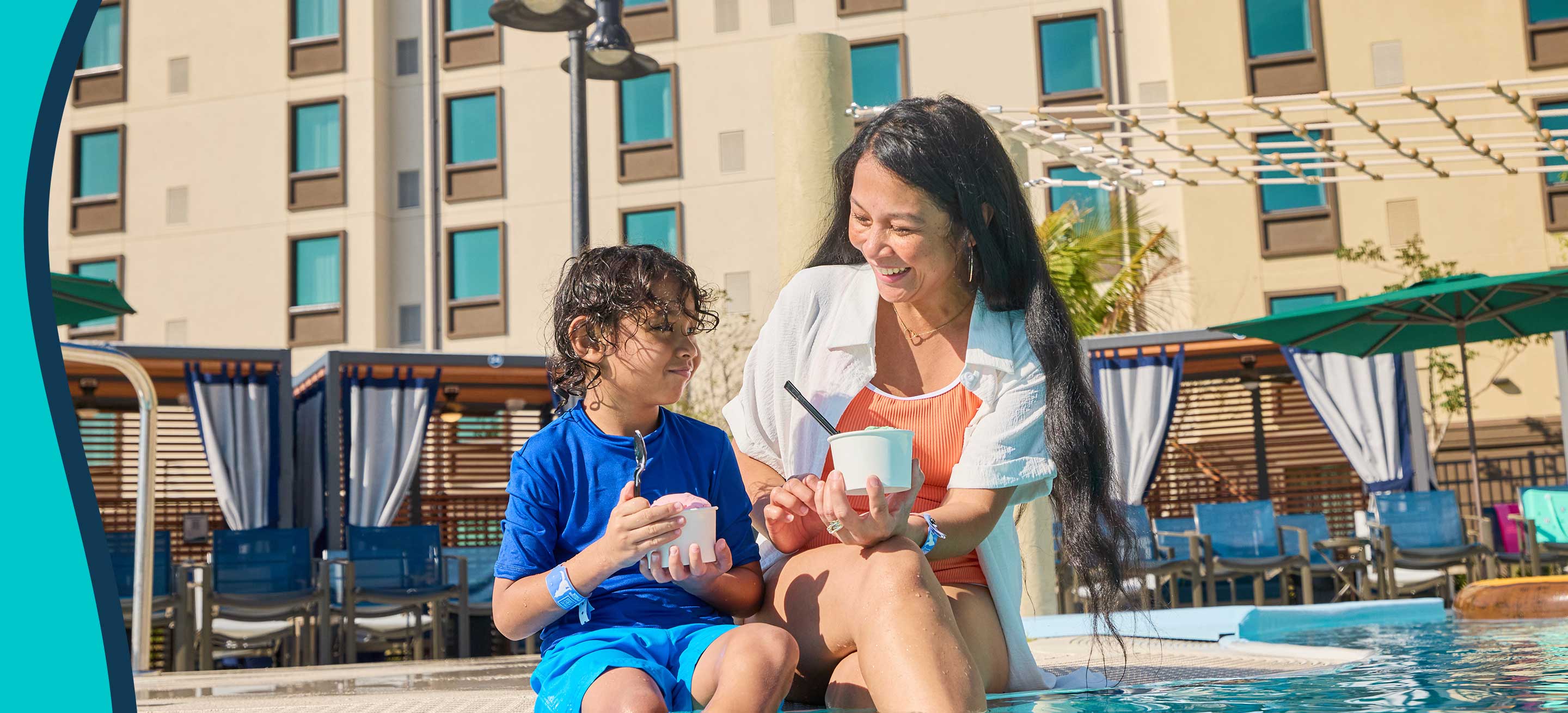 mother and kid sitting by the pool eating icecream