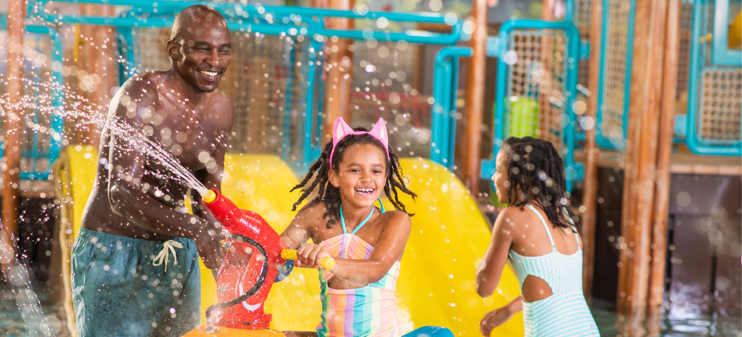 A father with two daughters splashing around in the water park.