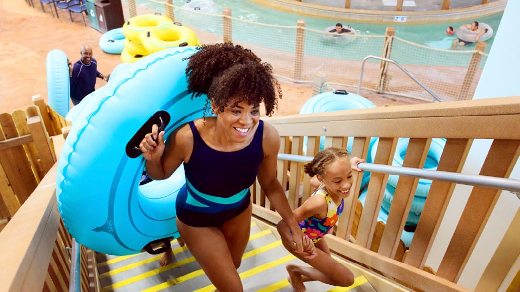 Mother and daughter going up getting ready to go down a slide.