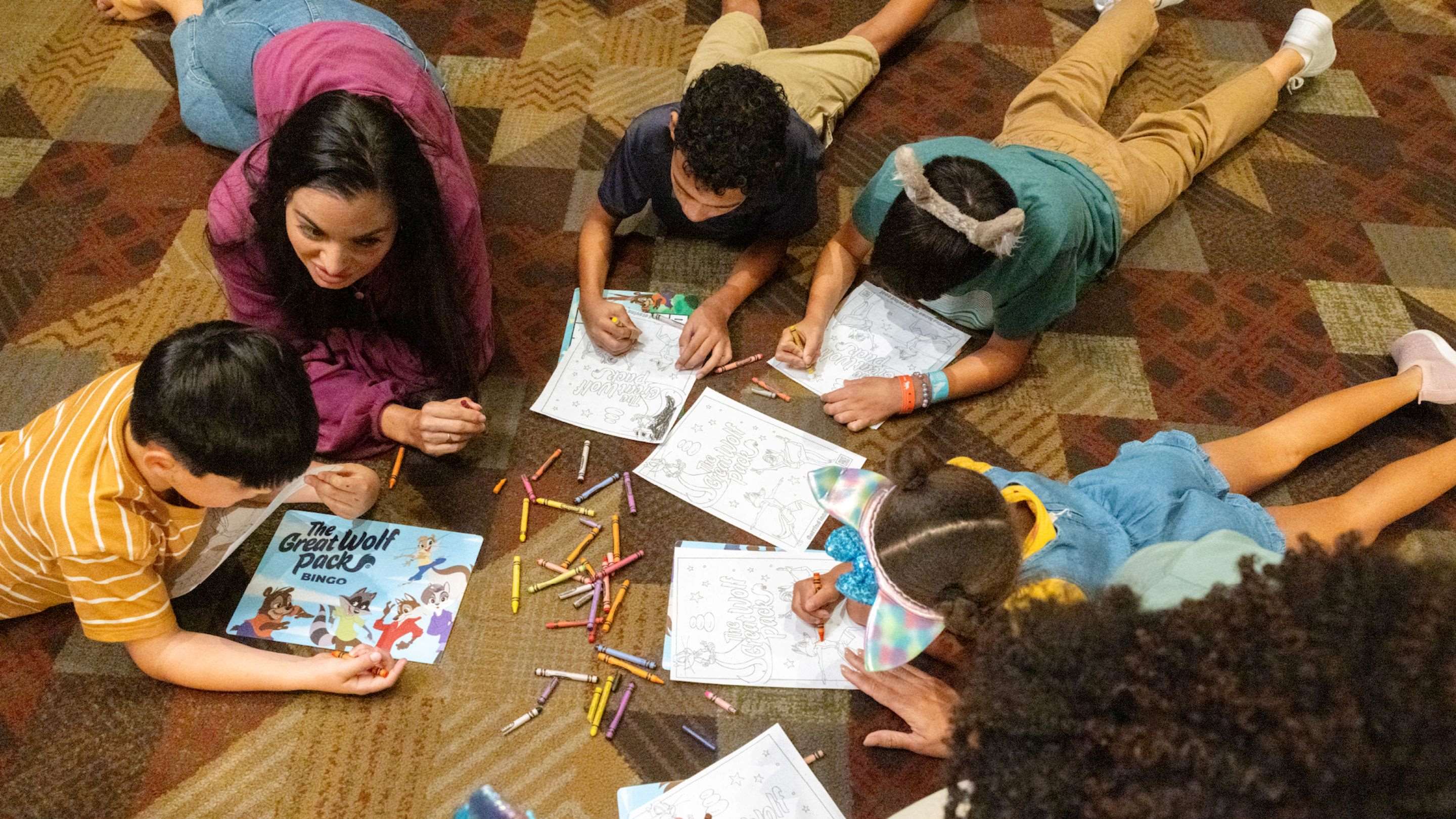 A group of diverse kids coloring on the floor together.