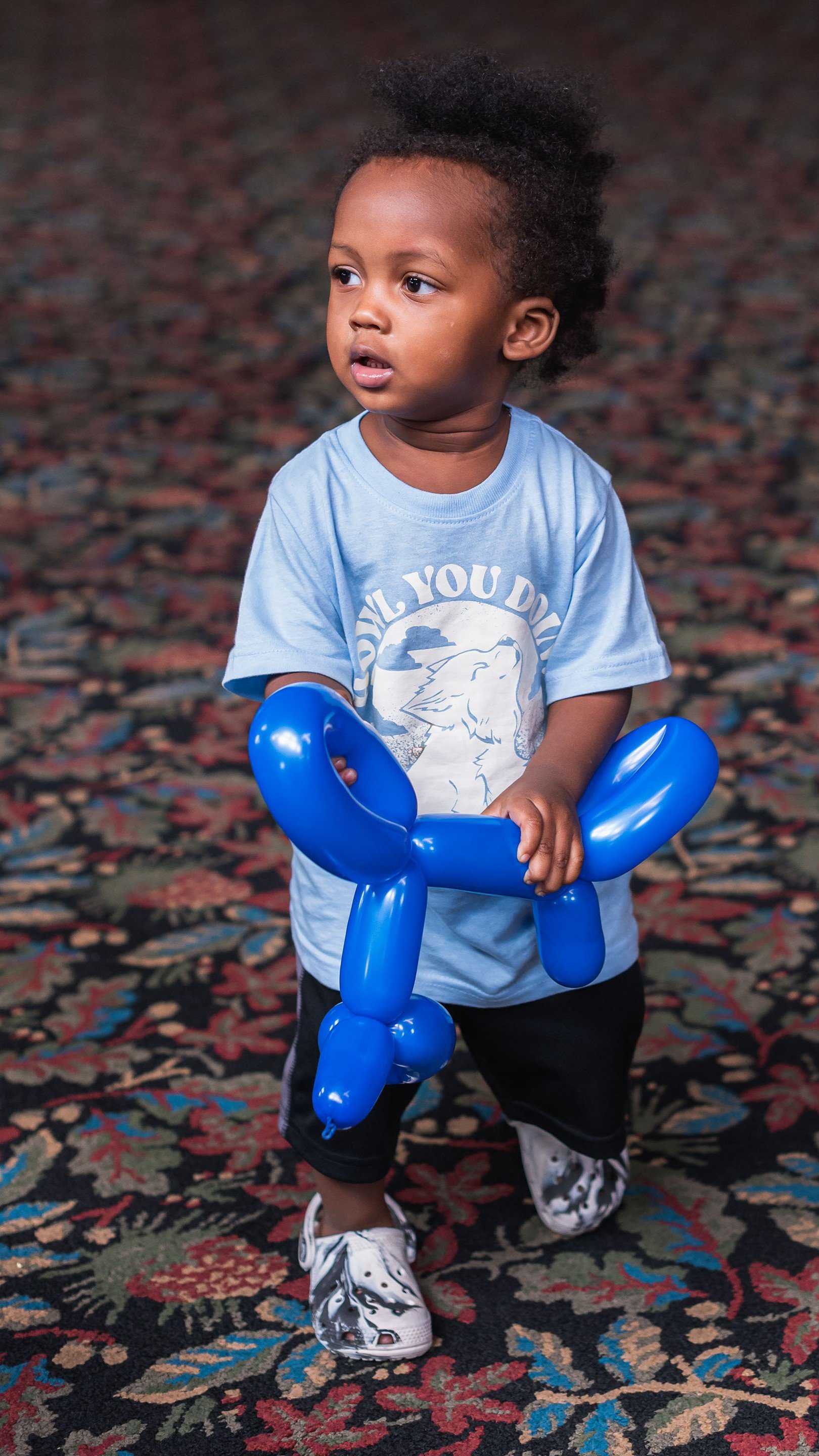 Kid holding a blue color twisted balloon