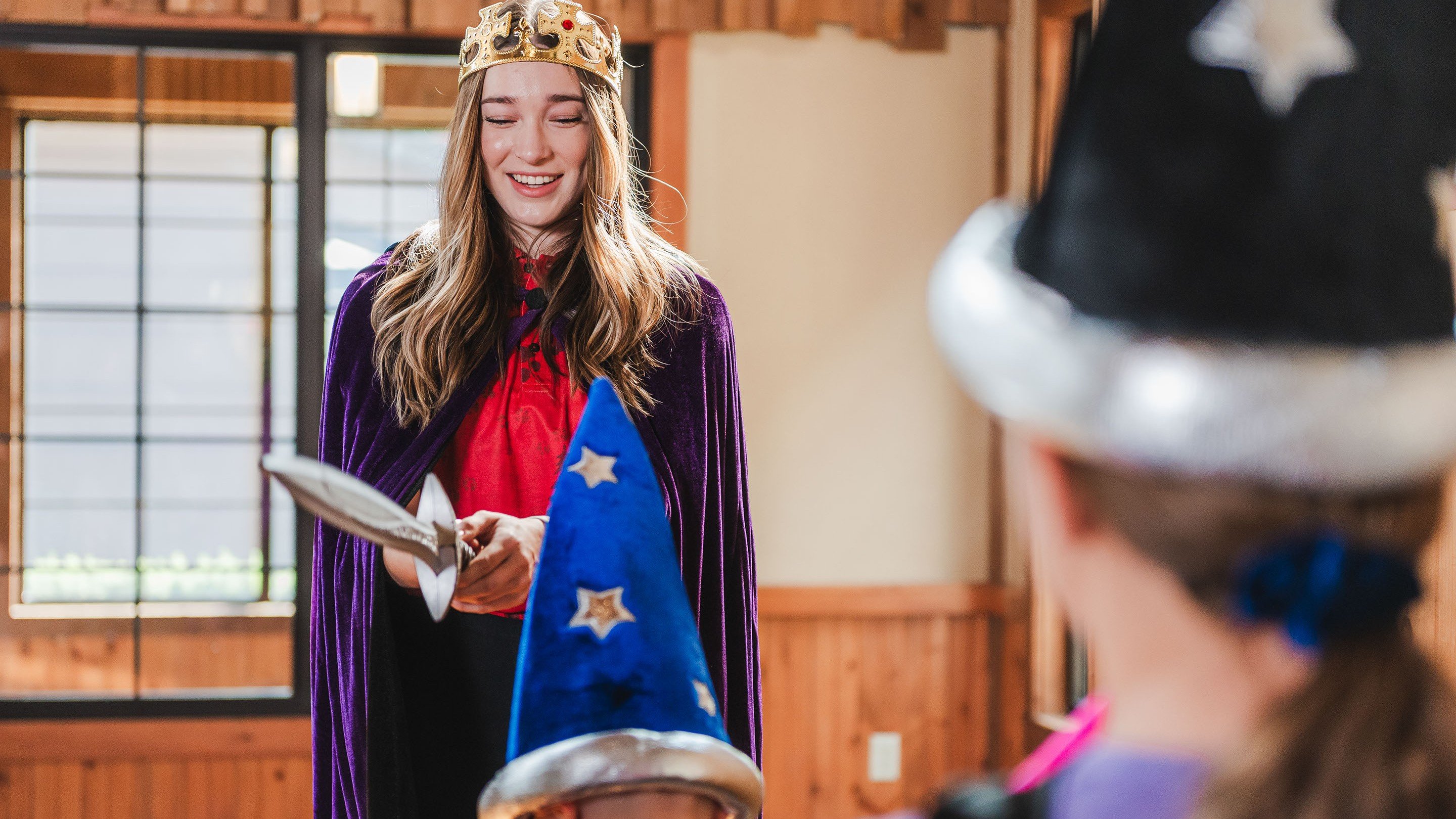 Woman in crown knighting child in costume