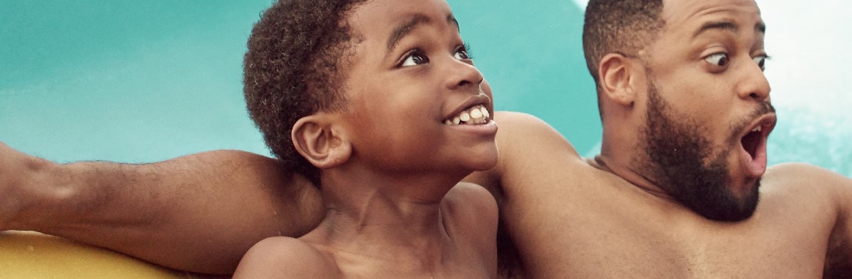 A father and son share a tube down a water slide