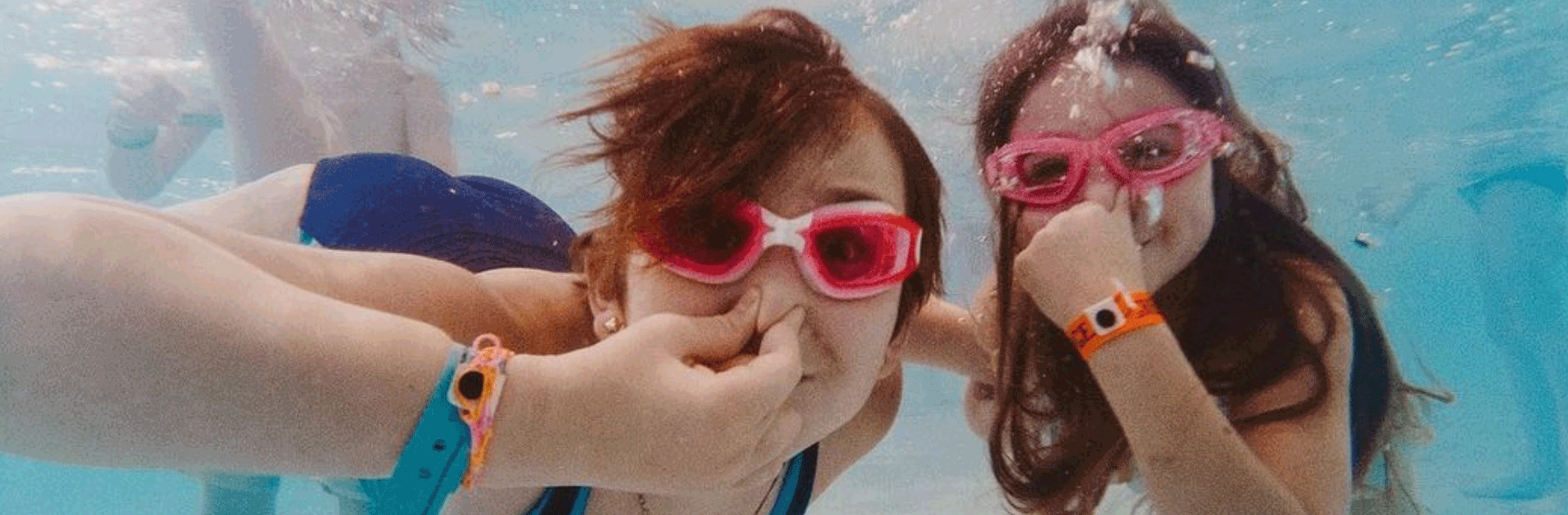 two girls wearing goggles in a swimming pool