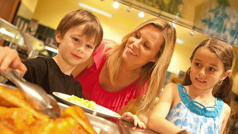 A boy uses tongs to grab food 