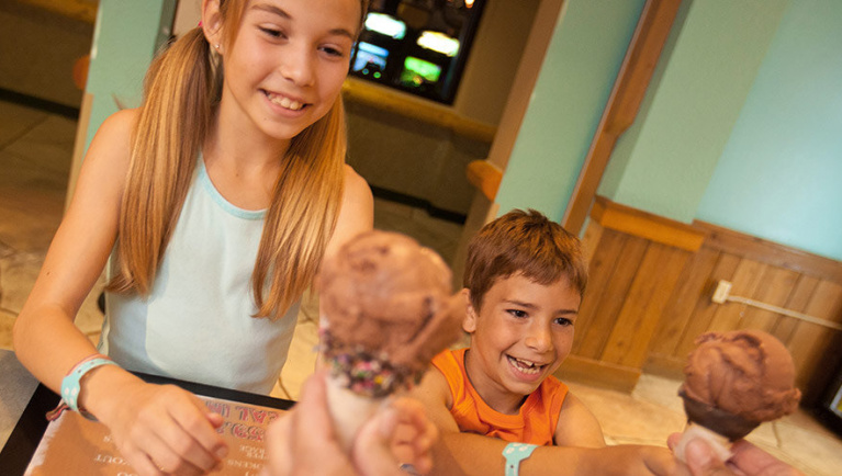 Two kids reach out for ice cream cones