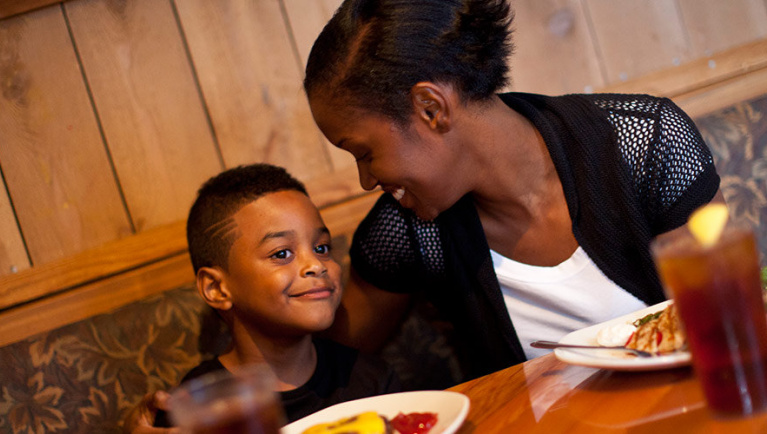A mother smiles at her son while dining 