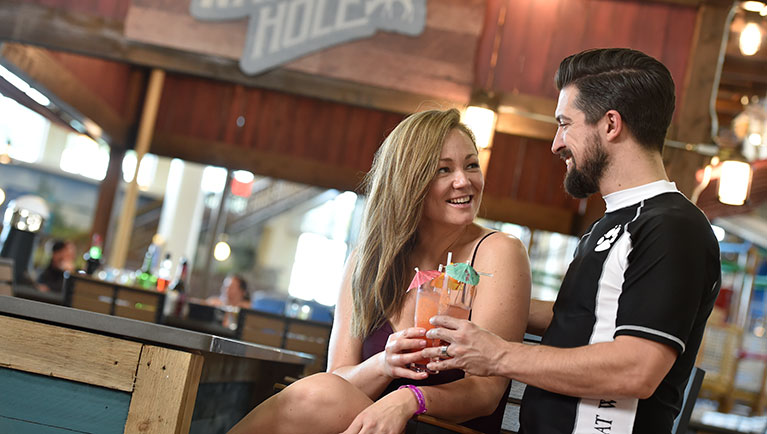 A couple smiles as they enjoy drinks 