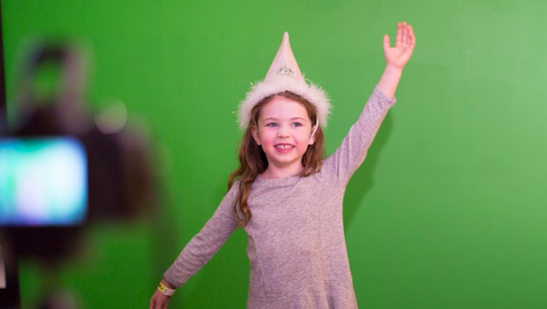 A girl wearing a pointed hat poses for a picture 