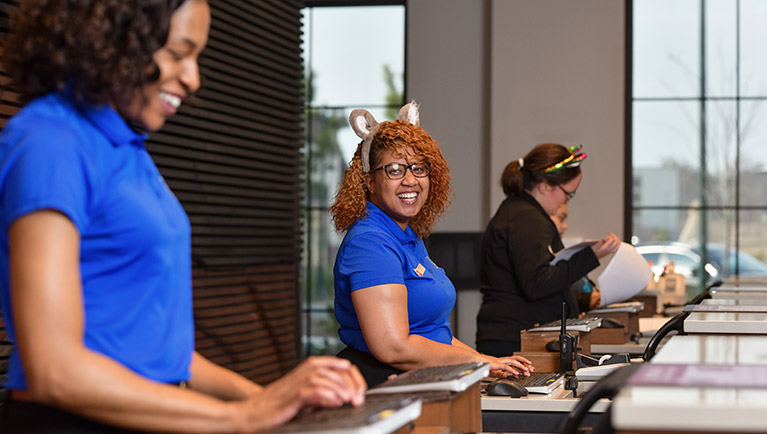 Customer Service members laugh and type at front desk