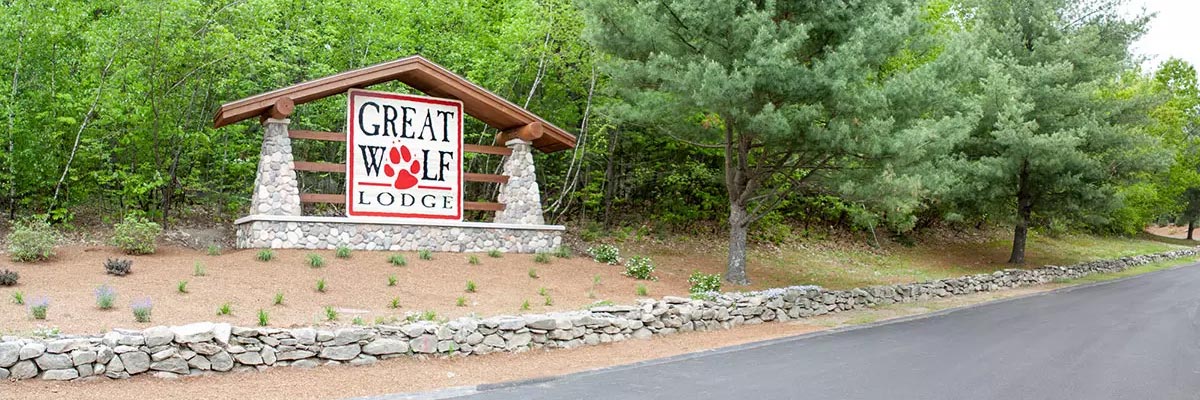 Lodge sign welcoming guests as they arrive at the resort in front of trees.