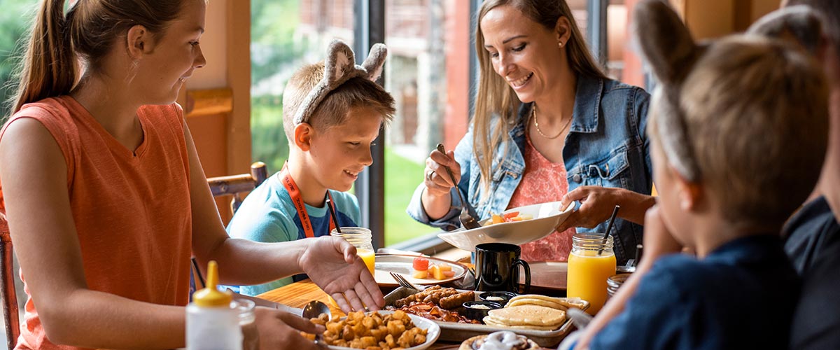 A mother smiles at her son and her daughter during dinner
