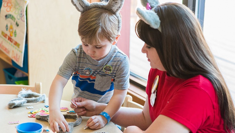 A Great Wolf Lodge pack member helps a child decorate wolf ears at Camp H.O.W.L. Kids Club at Great Wolf Lodge indoor water park and resort.