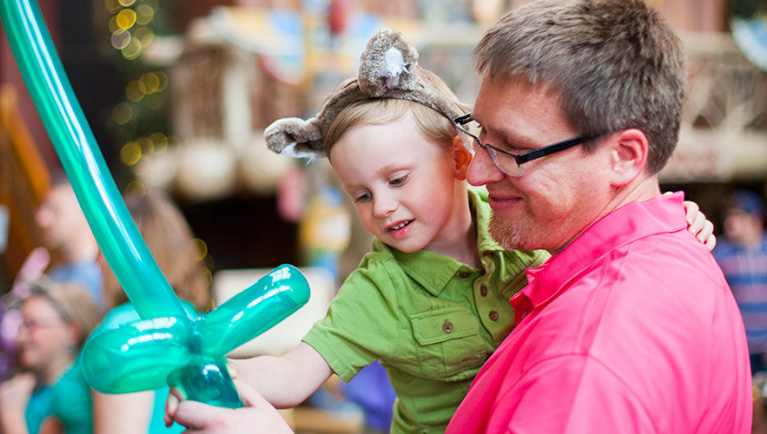 A father holds his son and a balloon sword