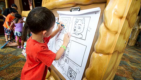 A boy colors and draws on paper