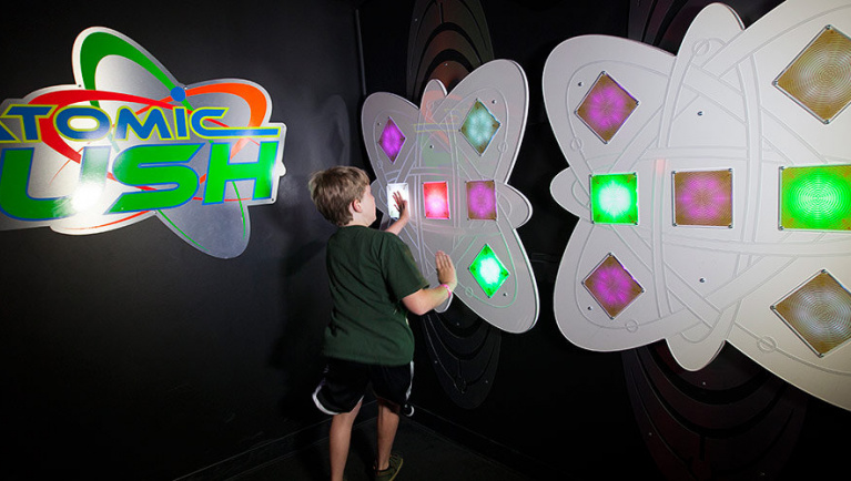 A boy presses light buttons playing AtomicRUSH at Great Wolf Lodge indoor water park and resort.