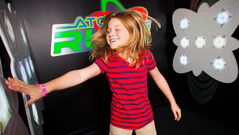 A girl presses light buttons playing AtomicRUSH at Great Wolf Lodge indoor water park and resort.
