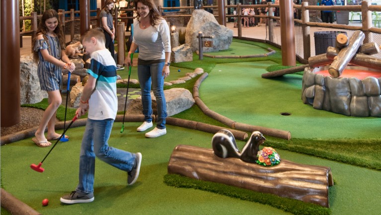 A father and son at the Howl at the Moon Mini Golf counter at Great Wolf Lodge indoor water park and resort.