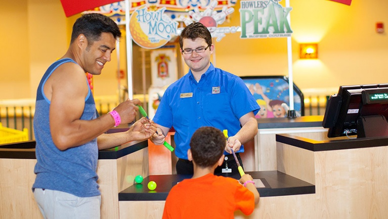 A father and son at the Howl at the Moon Mini Golf counter at Great Wolf Lodge indoor water park and resort.