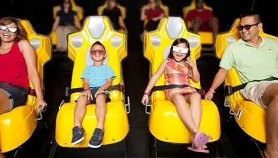 A family of four wear 3D glasses inside the Howly Wood XD Theater at Great Wolf Lodge indoor water park and resort.