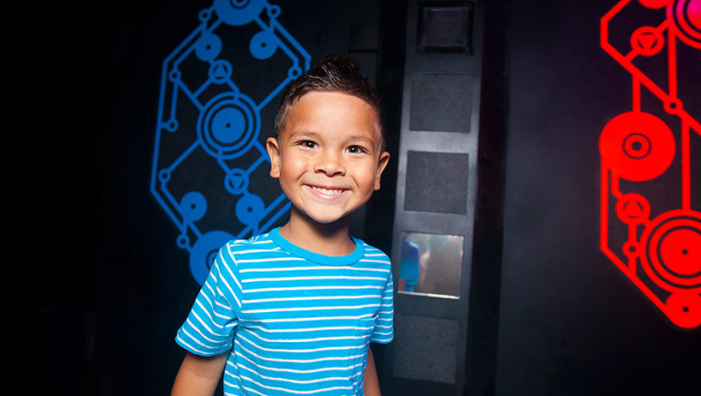 A boy smiles at Lazer Frenzy at Great Wolf Lodge indoor water park and resort.