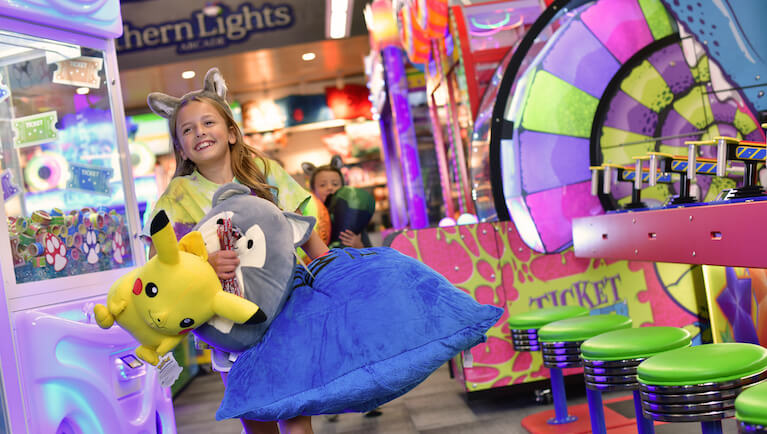A girl holds up her prizes at Northern Lights Arcade at Great Wolf Lodge indoor water park and resort.