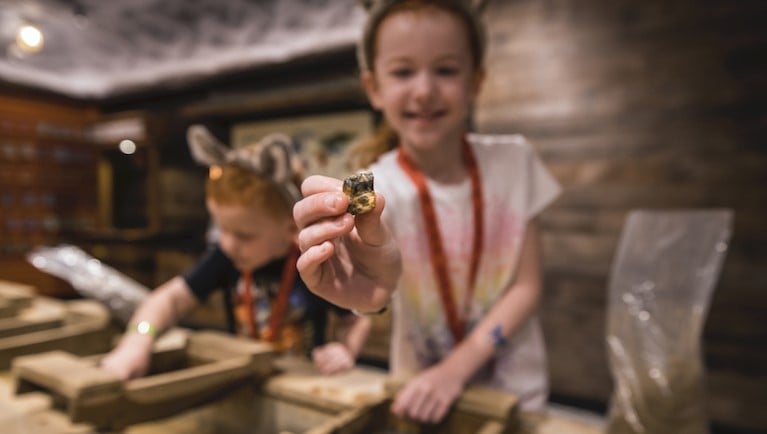A girl holds up a gem at  Oliver's Mining Co. 