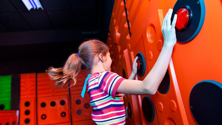 A girl presses buttons playing Oliver's Time Challenge at at Great Wolf Lodge indoor water park and resort.