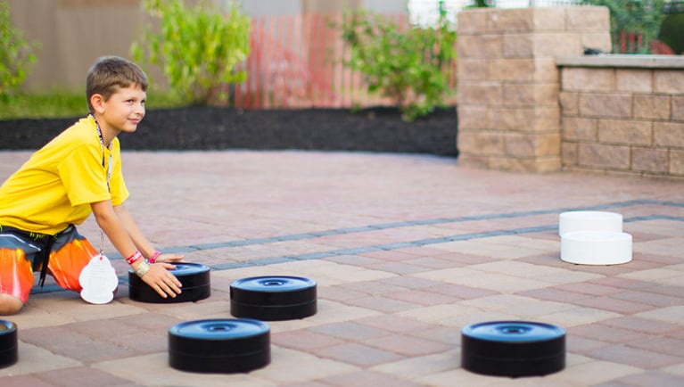 A boy moves giant checker pieces