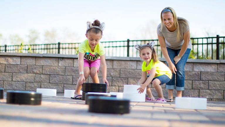 A mother and her daughters move giant checker pieces