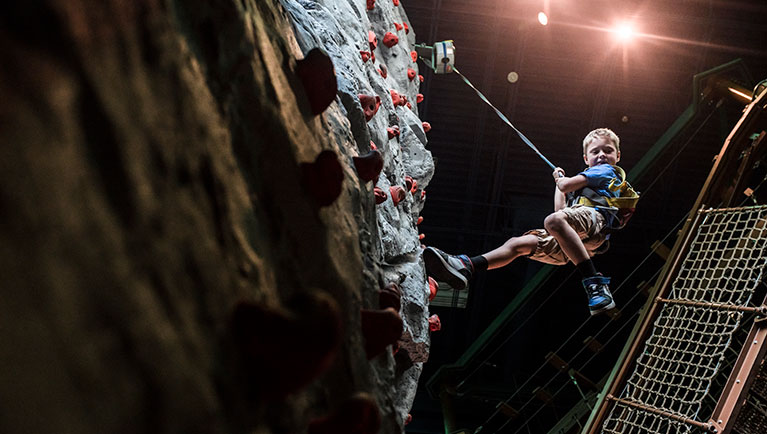 A boy climbs a rock wall at Great Wolf Lodge Indoor waterpark and resort
