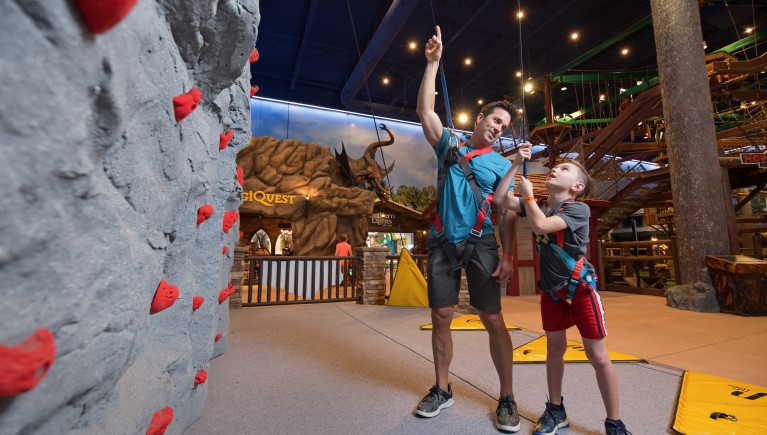 Father and son try to climb a rock wall at  Great Wolf Lodge indoor water park and resort indoor water park 