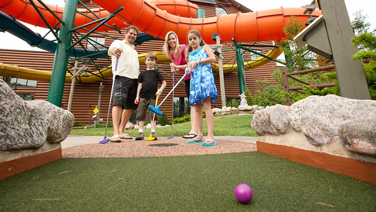 A family of four plays a round of mini golf 