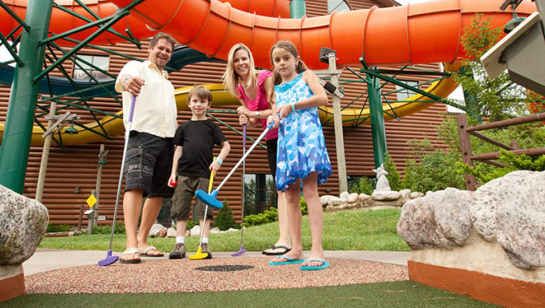 A family of four play indoor mini golf