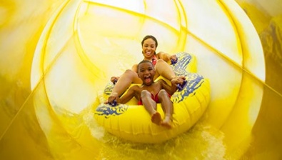 Mother and son in a tube racing down a yellow waterslide 