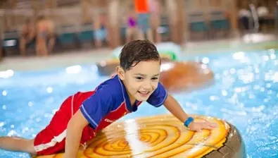 A boy balances on a lily pad float in the Big Foot Pass pool at Great Wolf Lodge indoor water park and resort.