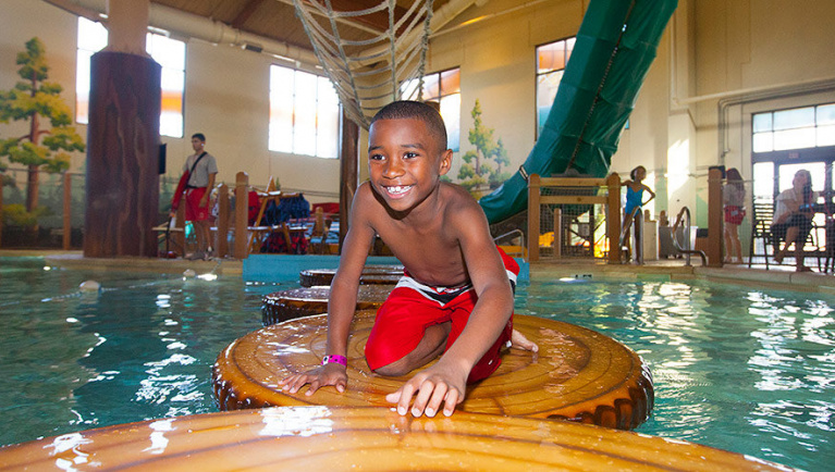 A boy balances himself on a float in the Frog Bog Log Walk pool at Great Wolf Lodge indoor water park and resort.
