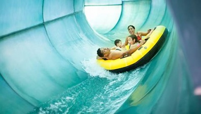 Family of four rides down waterslide in yellow tube