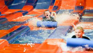 A father and son finish the Mountain Edge Raceway water slide at Great Wolf Lodge indoor water park and resort.
