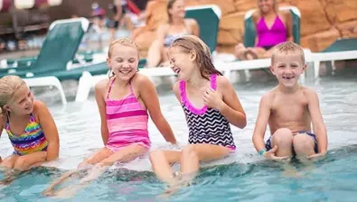 Four kidslaugh and  jump into outdoor pool