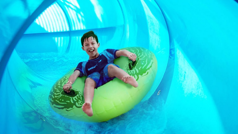 A boy rides a tube down Rapid Racer at Great Wolf Lodge indoor water park and resort.