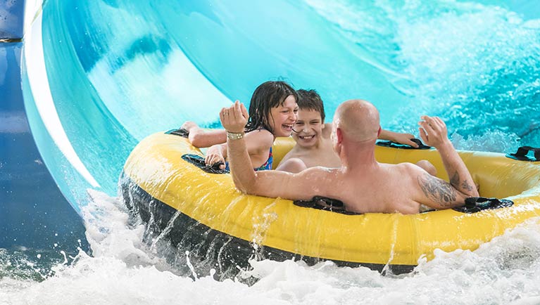 A family laughs as they tube down River Canyon Run at Great Wolf Lodge indoor water park and resort.