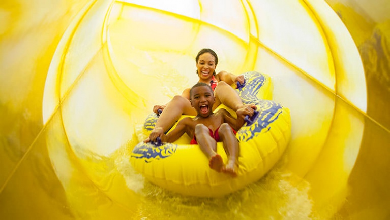 A mother and son ride a tube down Triple Thunder at Great Wolf Lodge indoor water park and resort.
