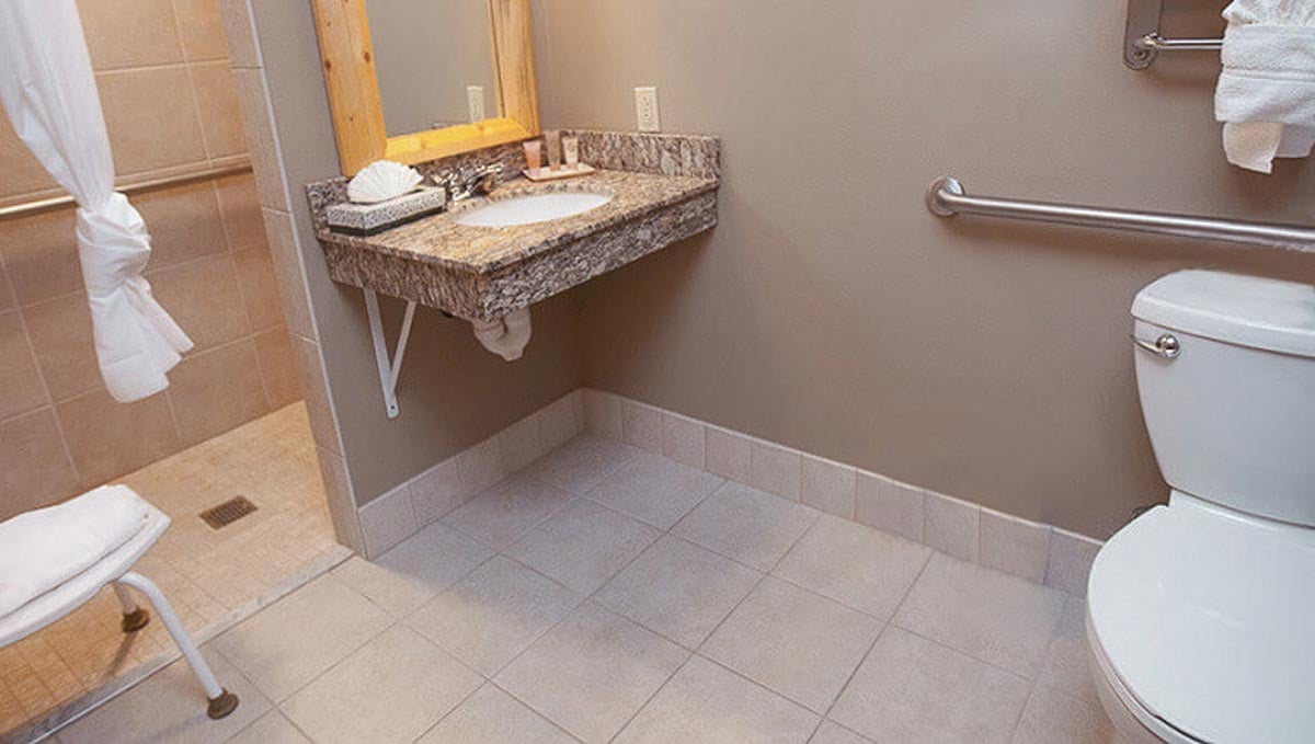 The bed and bathroom in the Accessible Bear Cub Suite