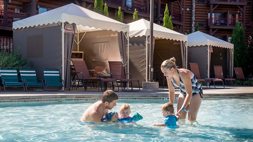 Family plays in pool by the Outdoor Cabanas