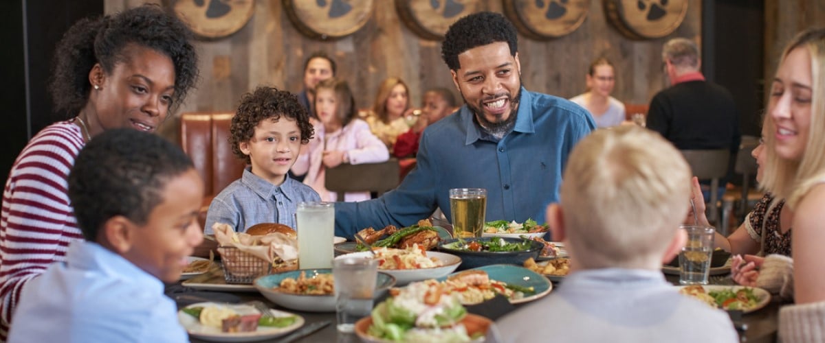 A mother smiles at her son and her daughter during dinner