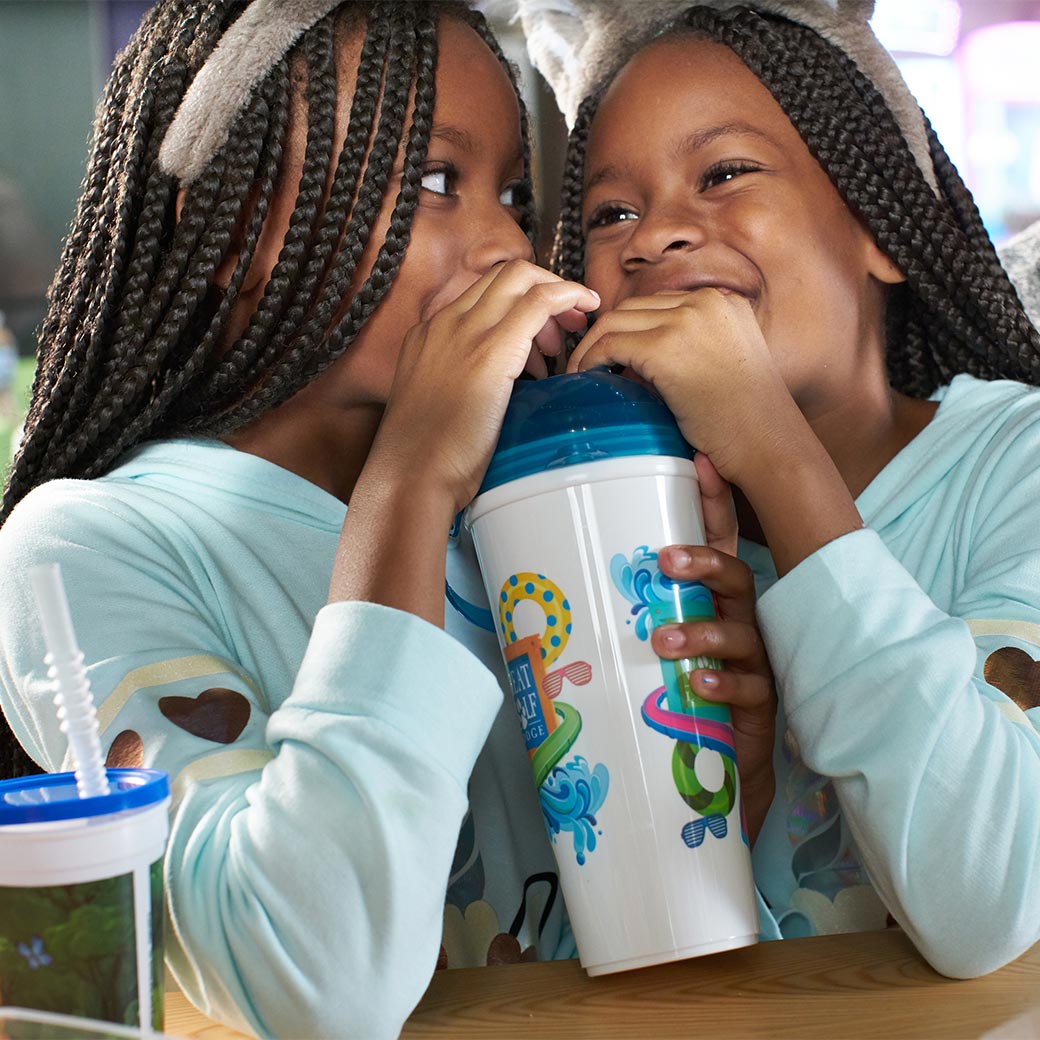 two girls sipping a drink from a cup